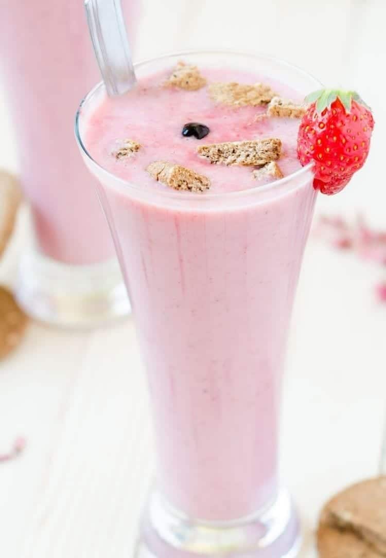 Pink strawberry low sugar smoothie with fresh strawberries in a tall glass.
