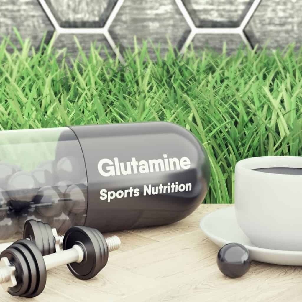 Glutamine sports nutrition supplements on a table with dumbells and coffee.