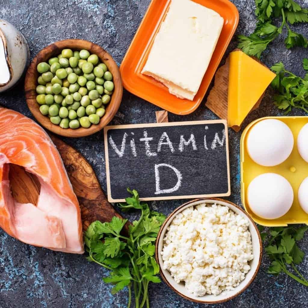 Foods like eggs, dairy, cheese, salmon on a blue countertop. Important vitamin D foods.