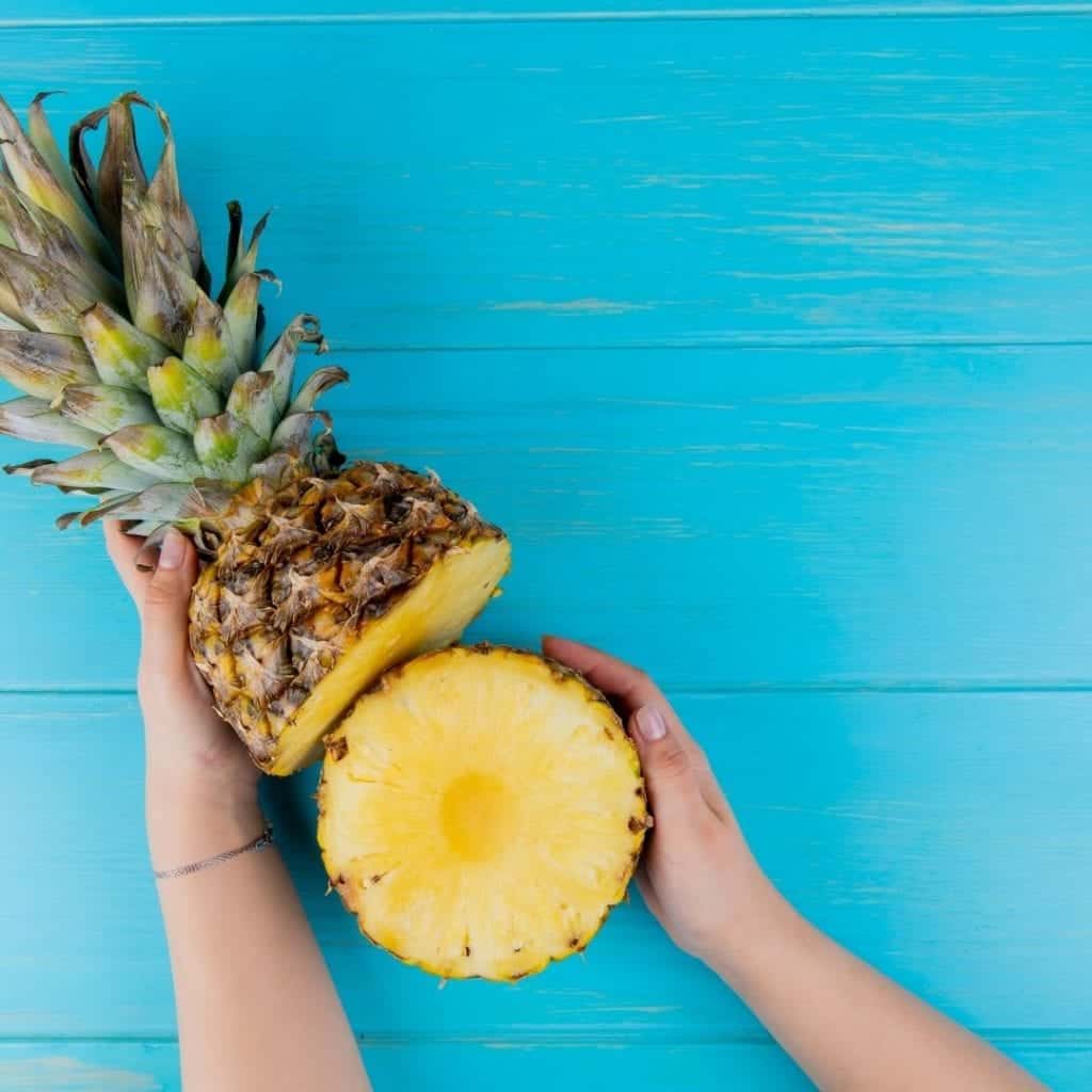 A person holding a cut pineapple wondering is pineapple good for arthritis sufferers?