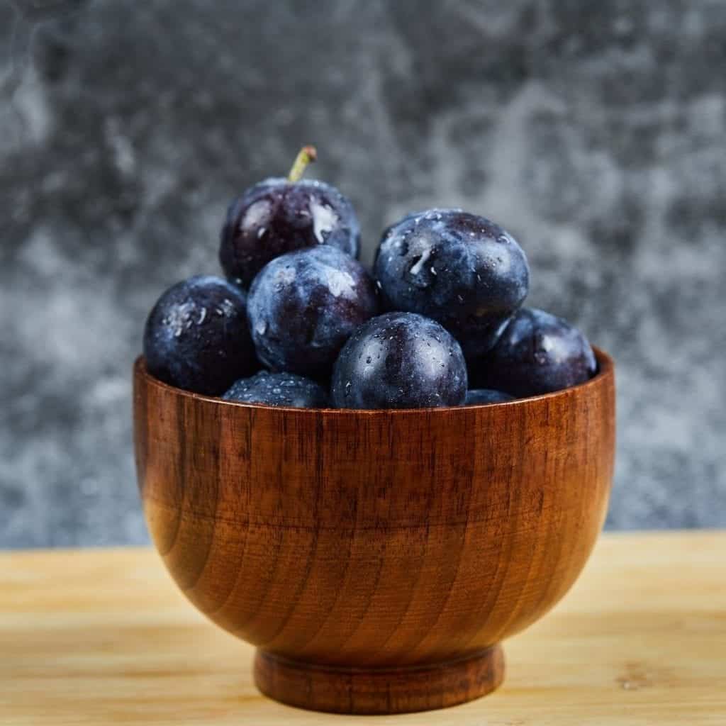 Wooden bowl with fresh plums. 