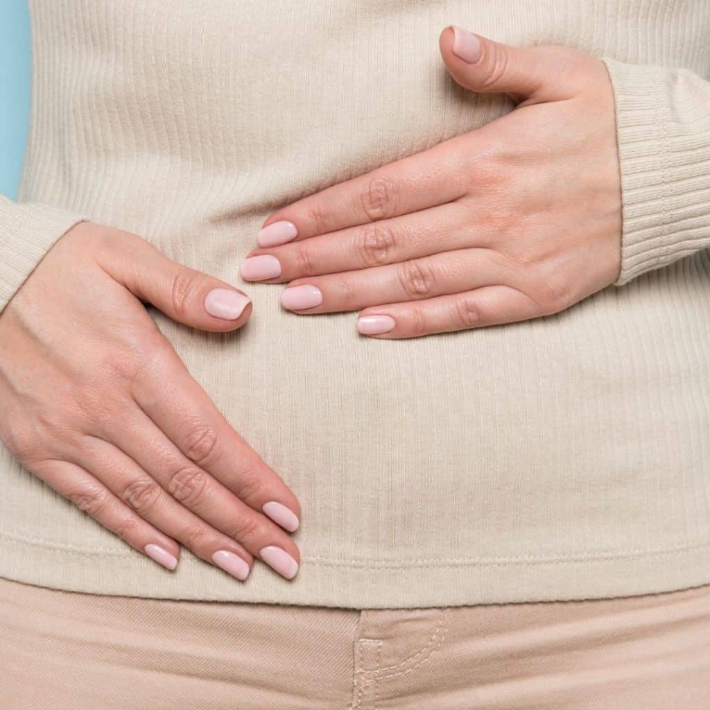 Woman holding stomach trying to stop the bloating feeling. 