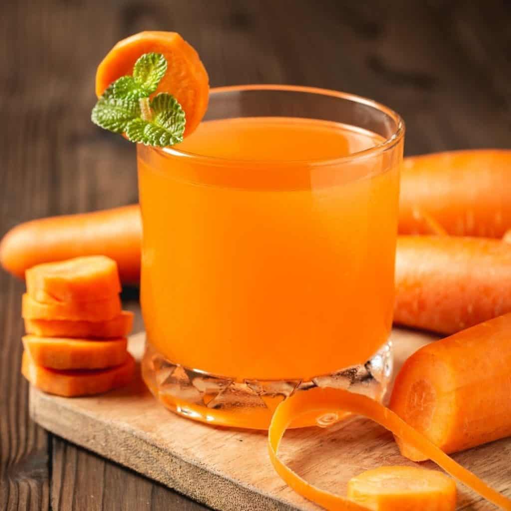Fresh carrot juice in a glass with raw carrots has amazing health and beauty benefits for the skin. 