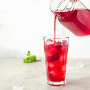 Iced Red raspberry rooibos healthy tea recipe being poured into a glass.