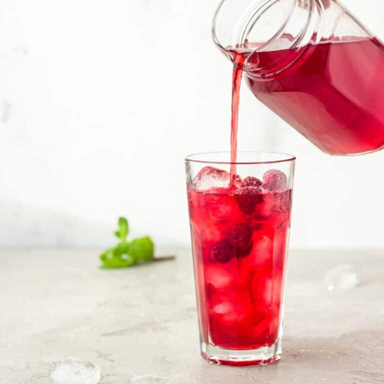 Iced Red raspberry rooibos healthy tea recipe being poured into a glass.