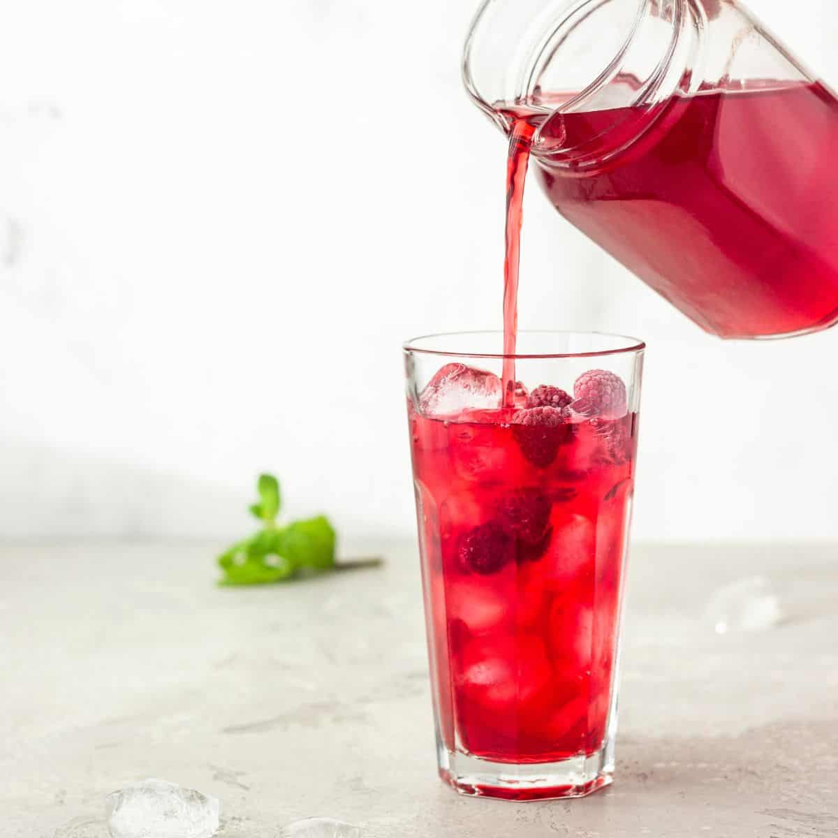 Iced Red raspberry rooibos healthy tea recipe being poured into a glass. 