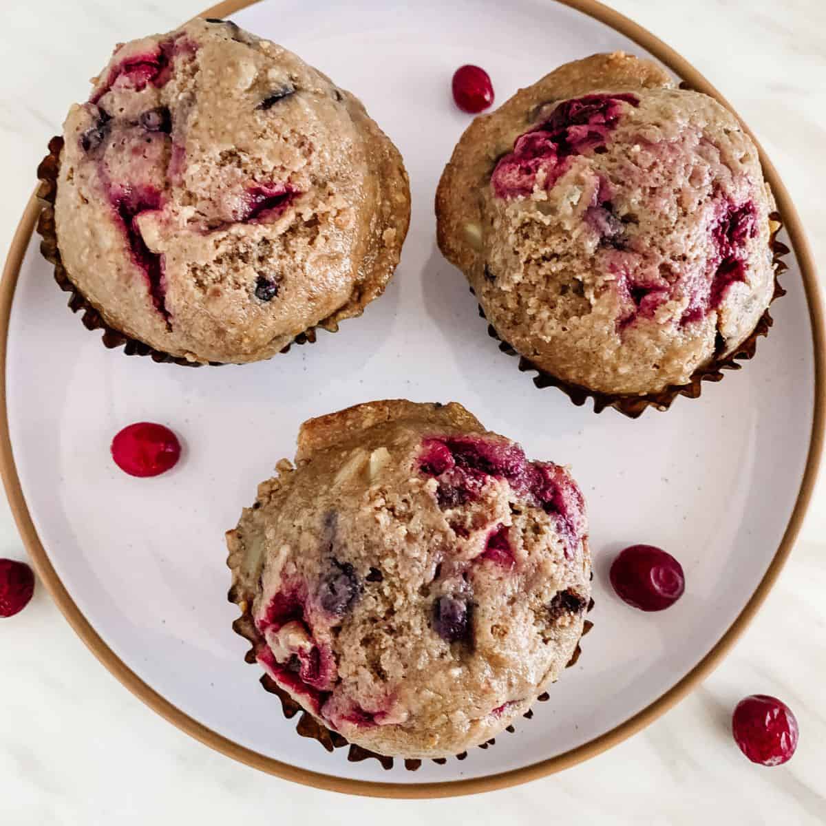 Vegan superfood mixed berry muffins on a ceramic plate with blueberry and cranberries.