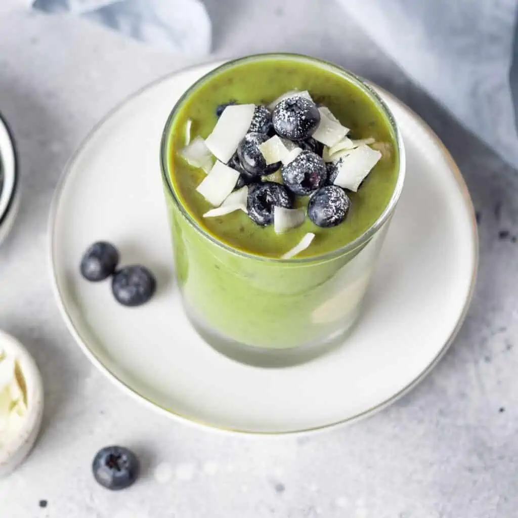 Delicious hormone-balancing green smoothie topped with fresh blueberries and coconut flakes, gluten free recipe for good gut health and healing.