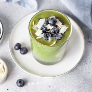 Delicious hormone-balancing green smoothie topped with fresh blueberries and coconut flakes, gluten free recipe for good gut health and healing.