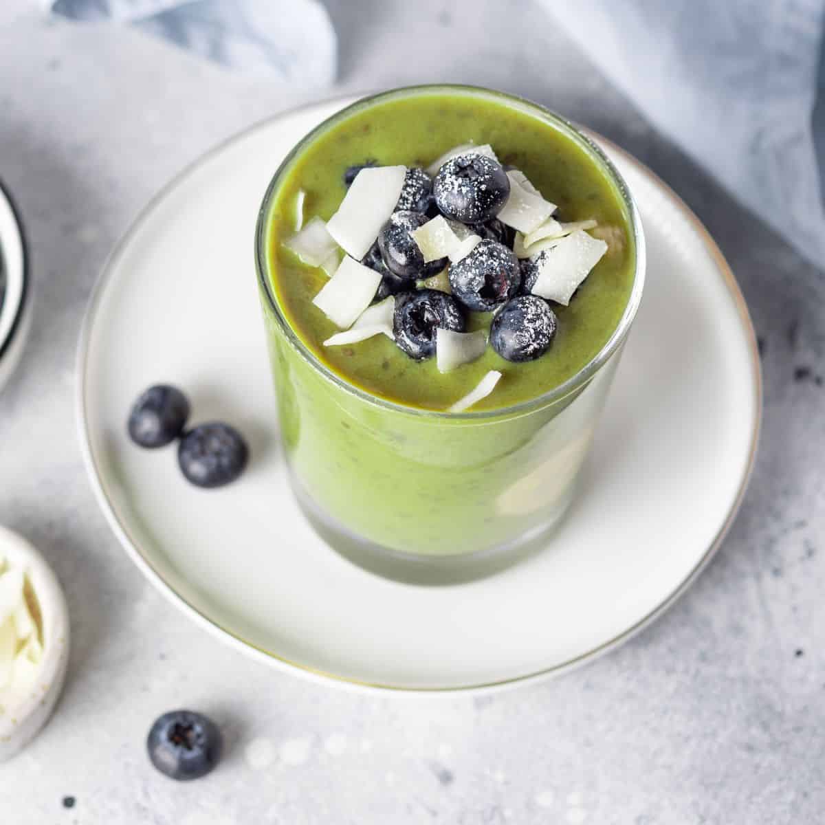 Delicious hormone-balancing green smoothie topped with fresh blueberries and coconut flakes, gluten free recipe for good gut health and healing.