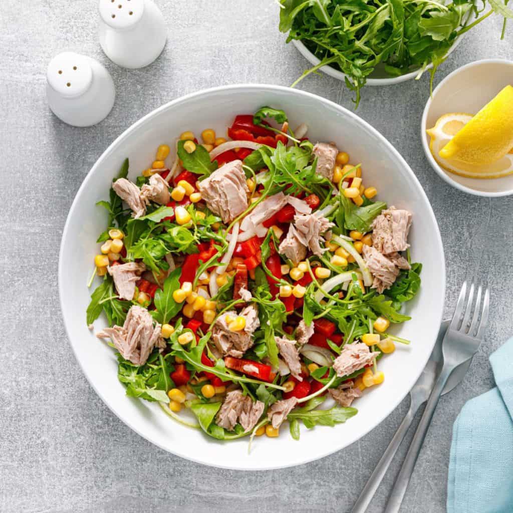 Healthy salad made with tuna, arugula, and fresh vegetables, typical healthy meal on a plate.