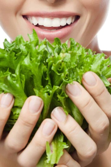 Woman holding lettuce, foods good for skin issues.
